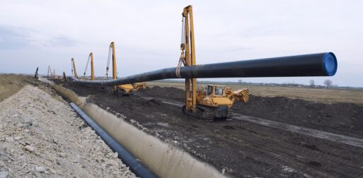 Heavy duty construction machines carrying and placing gas pipe into the ground.