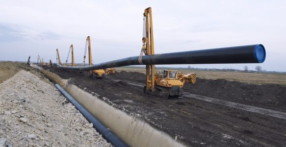 Heavy duty construction machines carrying and placing gas pipe into the ground.